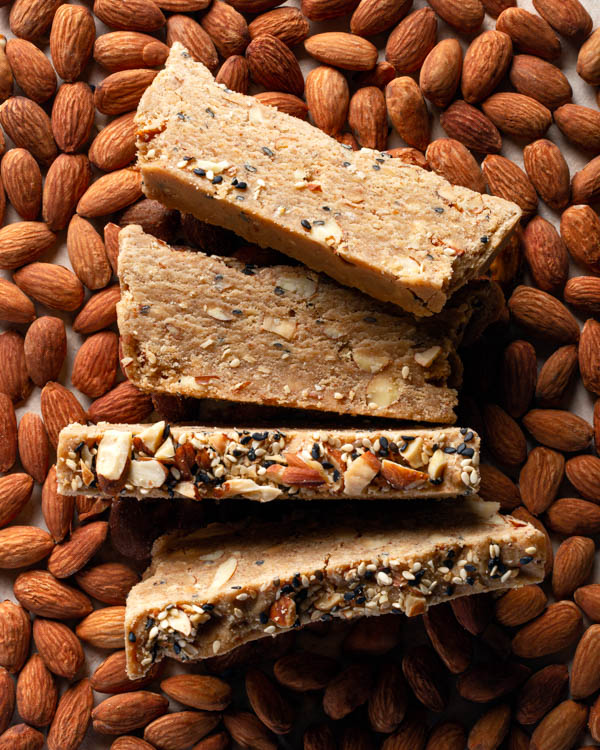 Tranches de halva aux amandes sur un lit d'amandes crues