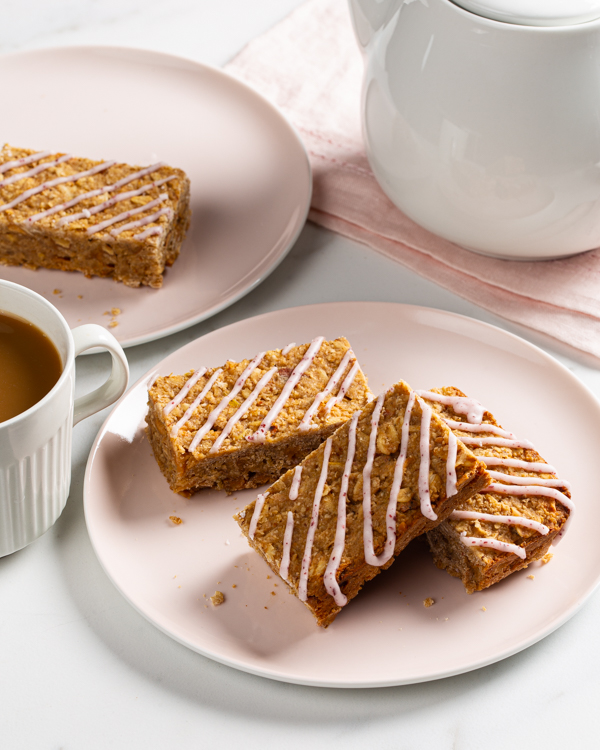 Barres avoine et pommes avec coulis citron-sumac dans une assiette avec une tasse de café et une cafetière