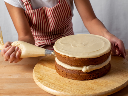 Presser du glaçage sur les côtés d’un gâteau étagé