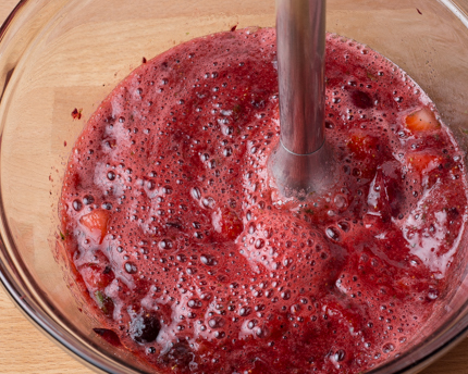 Fraises et cerises se faisant réduire en purée à l’aide d’un mélangeur à main