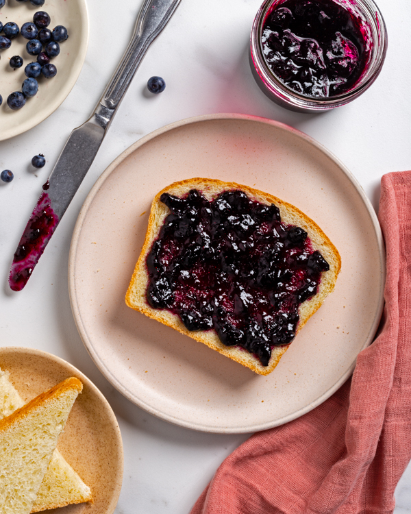 Une tranche de pain blanc avec de la confiture aux bleuets sur une assiette