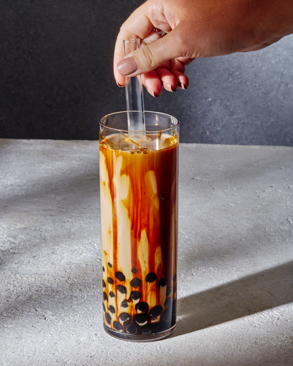 Deux verres de thé au lait boba hojicha avec de grandes pailles et une cuillère de perles de tapioca