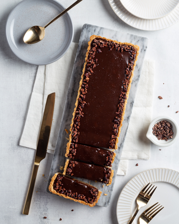 Une tarte à la ganache et aux châtaignes sur une table avec des assiettes et des couverts