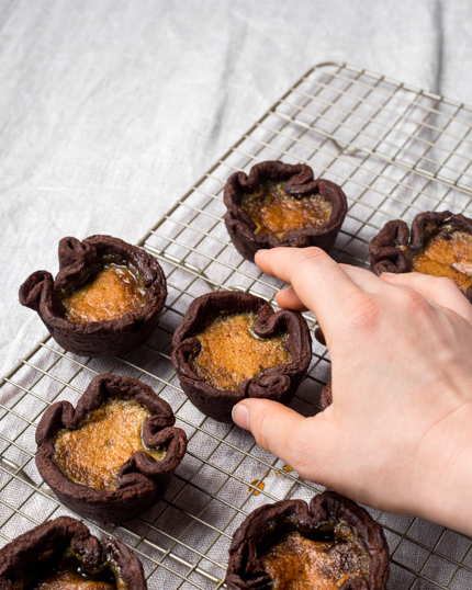 Des tartelettes au beurre chocolatées se faisant transférer sur une grille de refroidissement