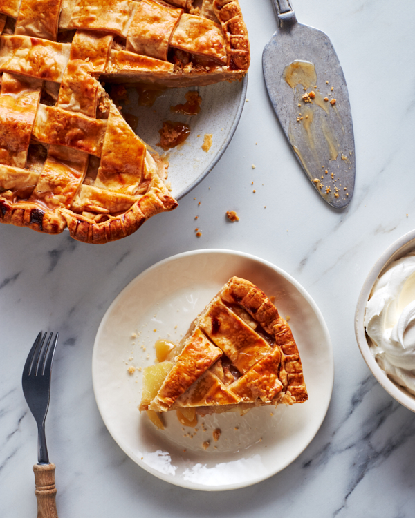 Tarte aux pommes en treillis sur un plateau avec une tranche coupée et servie sur une assiette