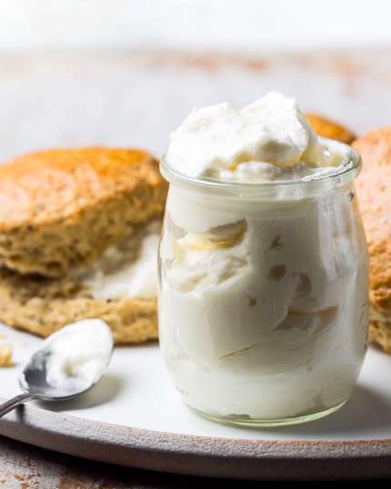 Gros plan sur un pot en verre rempli de crème caillée Devonshire et des scones