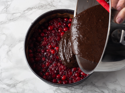 Verser l’appareil à gâteau au chocolat sur les canneberges dans un moule à charnière