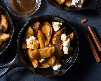 Une poêle en fonte pleine de poutine dessert incluant les tranches de pommes, la sauce au caramel et le fromage à la crème sucré