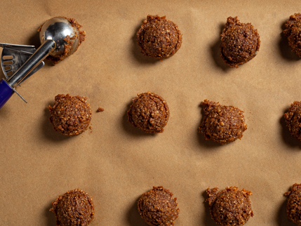 Boules non roulées de mélange noisettes et figues sur papier parchemin avec une cuillère à crème glacée à gâchette