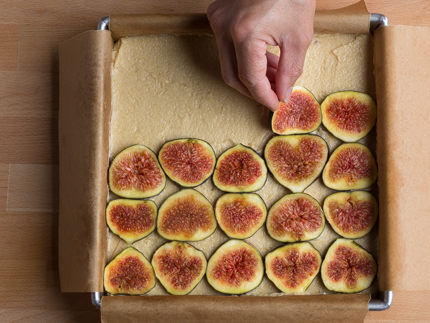 Tranches de figues se faisant déposer sur le dessert non-cuit étalé dans son moule