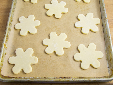 Biscuits crus en forme de fleurs sur une plaque à pâtisserie tapissée de papier parchemin