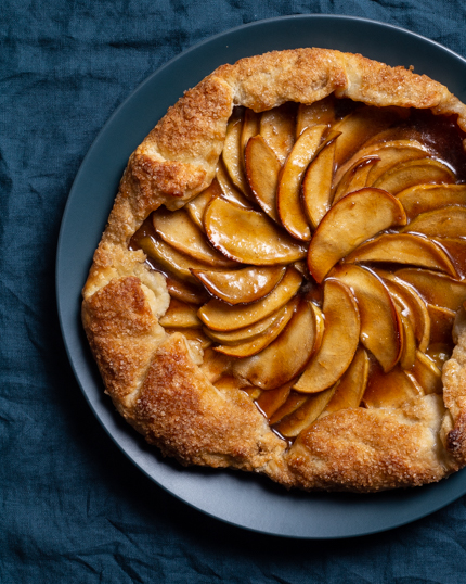 Galette aux pommes servie dans une assiette bleue, sur une nappe