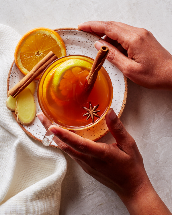 Un grog chaud dans une tasse en verre garnie de tranches d'orange, d'anis étoilé et de bâtons de cannelle