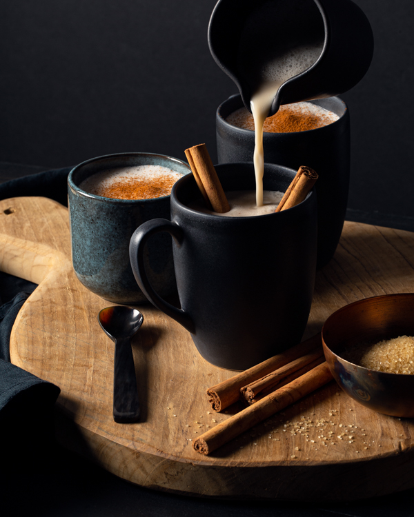 Verser l’horchata chaude d’un pichet dans une tasse avec des bâtons de cannelle