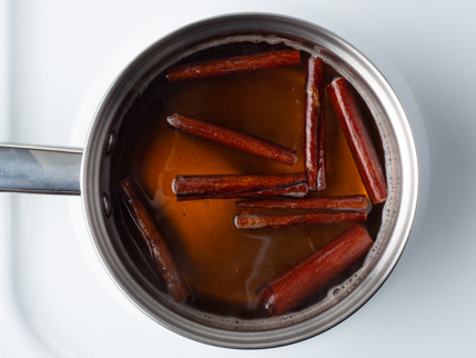 Mélange d’eau bouillante avec sucre turbinado dissout, sel et morceaux de bâtons de cannelle dans une casserole