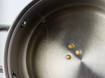 Trois grains de maïs à éclater dans l’huile au fond d’une grande casserole