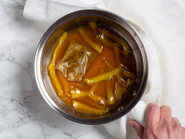 Sirop simple au citron dans une casserole avec un sachet de tisane et du zeste de citron