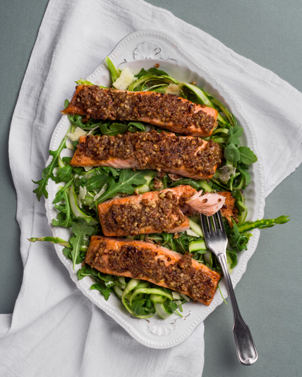 Salade de roquette avec filets de saumon dans un bol blanc déposé sur une serviette en tissu blanc