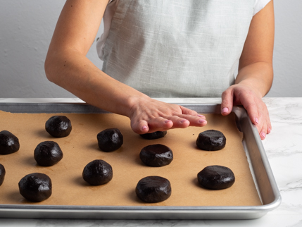 La paume d’une main écrasant les boules de pâte à biscuit au chocolat noir