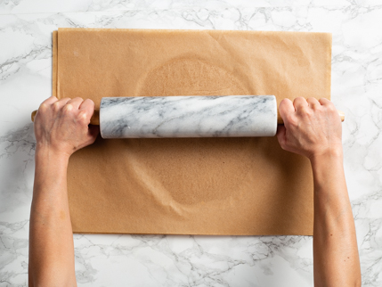 Abaisser la pâte entre des feuilles de papier parchemin à l’aide d’un rouleau à pâtisserie