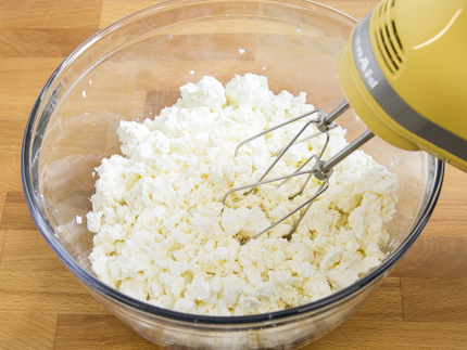 Fromage cottage et fromage à la crème dans un bol avec un batteur électrique