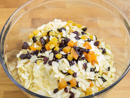 Un bol à mélanger en verre rempli d’amandes effilées, de raisins secs et de fruits séchés