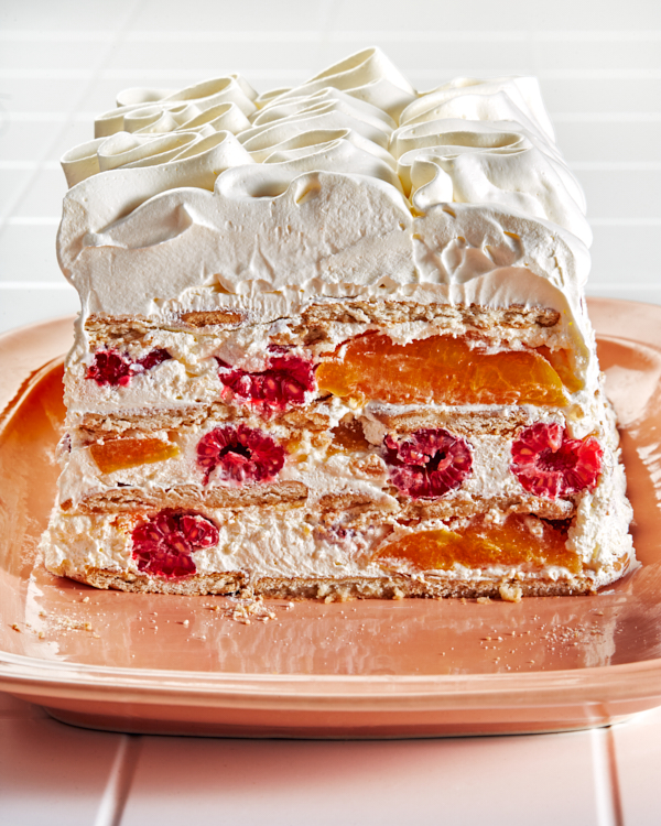 Gâteau glacé Peach melba vu de l'extrémité tranchée, révélant des couches de biscuits, de crème, de pêches et de framboises.