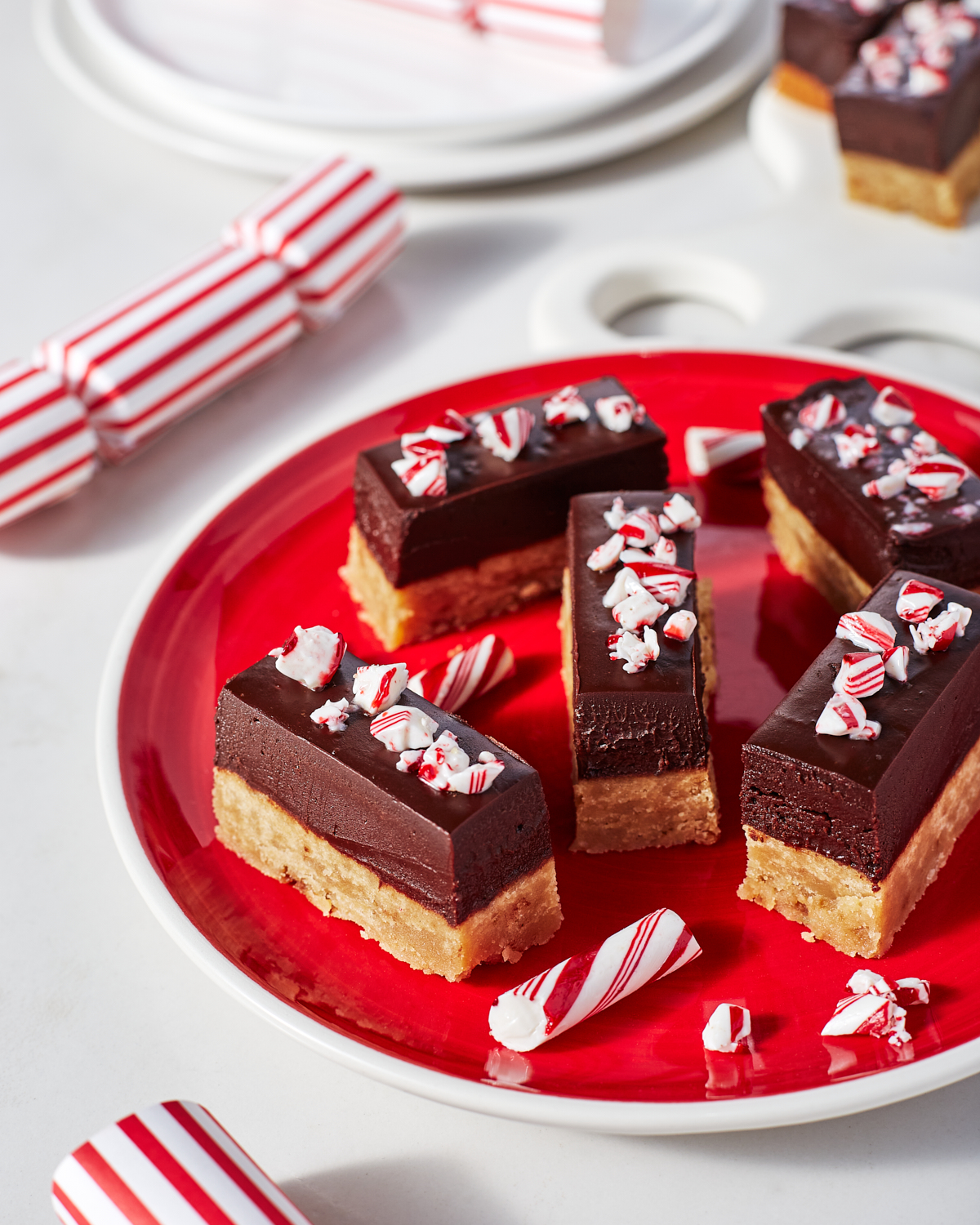 Barres de pâte à biscuits dorée recouvertes d’une ganache au chocolat assortie de morceaux de bonbons à la menthe poivrée sur une assiette rouge