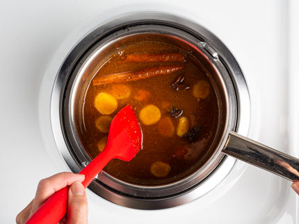 Remuer le sucre, l’eau, la cannelle, le gingembre et les épices dans une casserole sur le feu