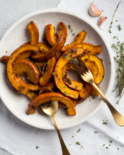  Morceaux de citrouille rôtie assaisonnée, présentés dans un plat avec fourchette et cuillère