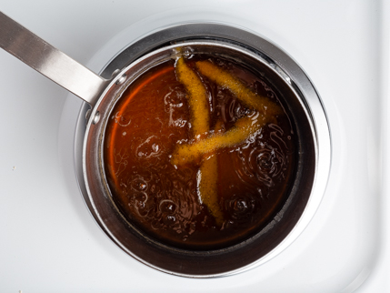 Casserole avec des lanières de zeste d’orange dans un sirop simple