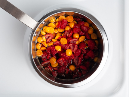 Casserole avec des framboises et groseilles coupées dans un sirop simple