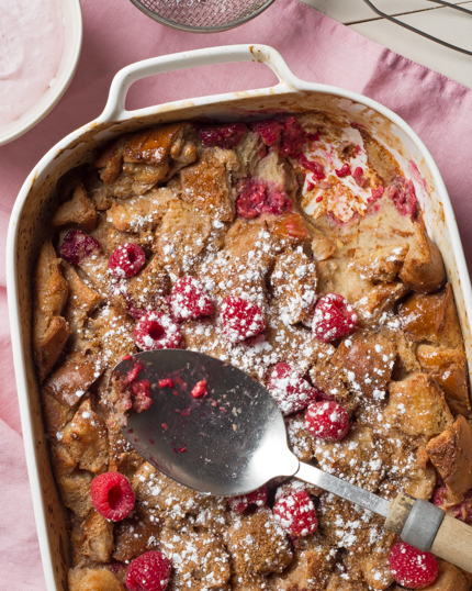 Plat de pouding au pain avec crème à la framboise et une cuillère de service