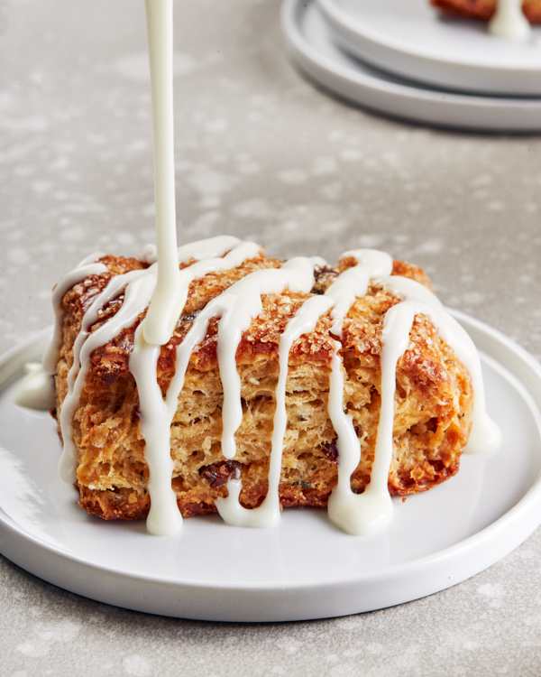 Un scone vanille-romarin-datte sur une assiette blanche avec un glaçage blanc coulant sur le dessus.