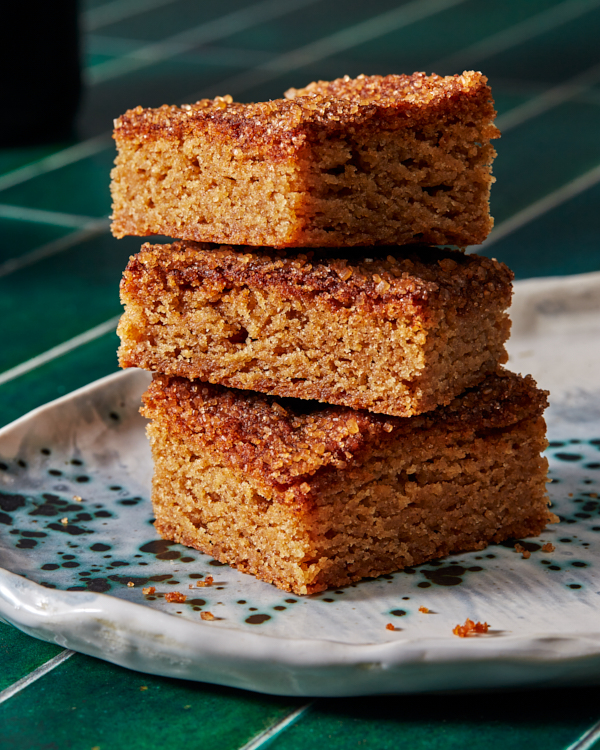 Trois barres de biscuits snickerdoodle empilées sur un plateau moucheté présenté sur un comptoir en carreaux verts.