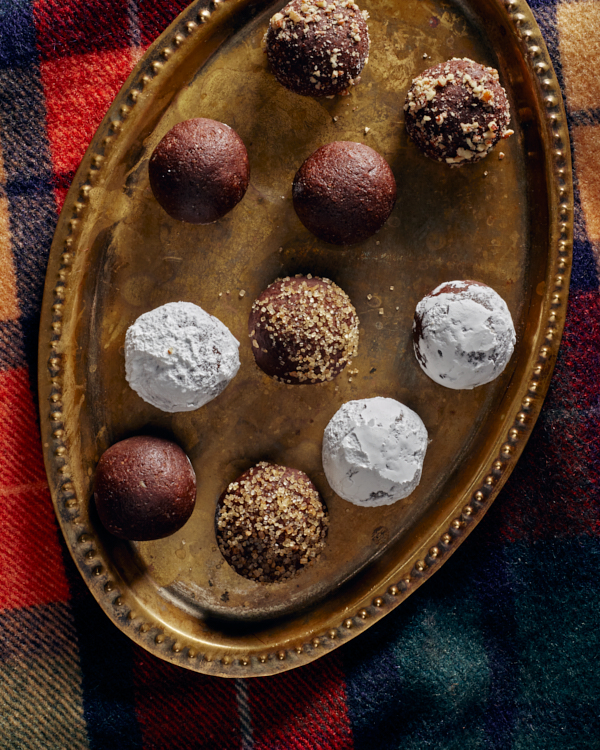 Boules de bourbon épicées sur un plateau en laiton sur une couverture à carreaux, garnies de sucre glace, de noix concassées et de sucre turbinado.