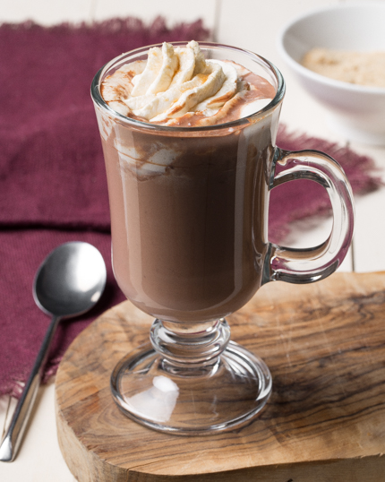 Du chocolat chaud dans une tasse en verre avec de la crème fouettée fondante sur le dessus