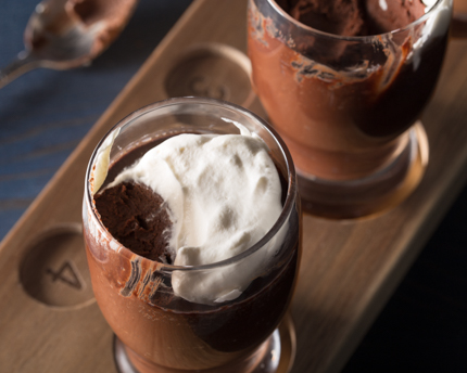 Deux pots de crème au chocolat partiellement mangés dans des verres de bière sur un plateau de dégustation