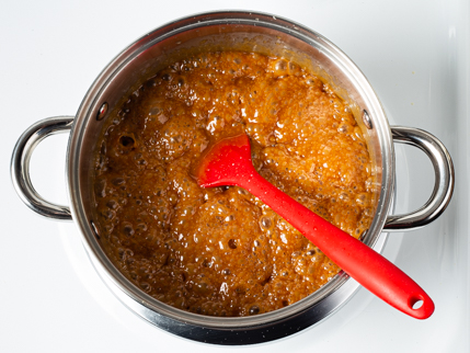 Le sucre et la crème qui bouillent dans une casserole sur une cuisinière