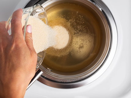  Verser du sucre biologique granulé d’un bol en verre dans une casserole remplie d’eau