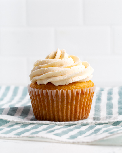 Un cupcake à la vanille avec glaçage à la crème au beurre sur un linge à vaisselle rayé