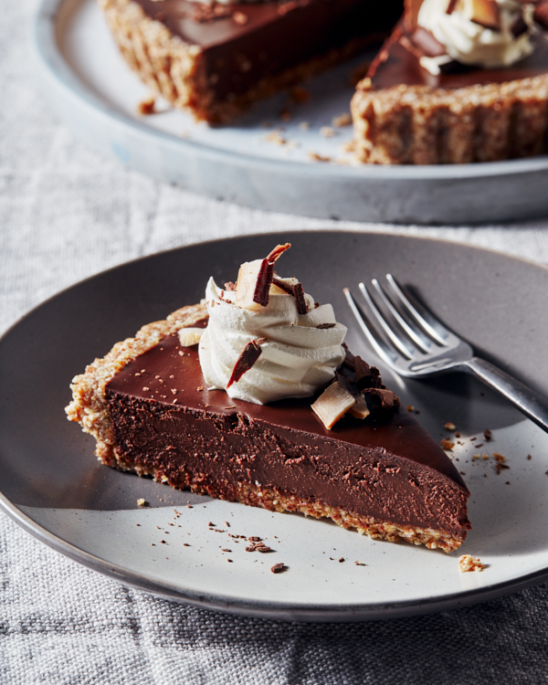 Tranche de tarte au chocolat chai végétalien sans cuisson sur une assiette bleu-gris avec une fourchette.