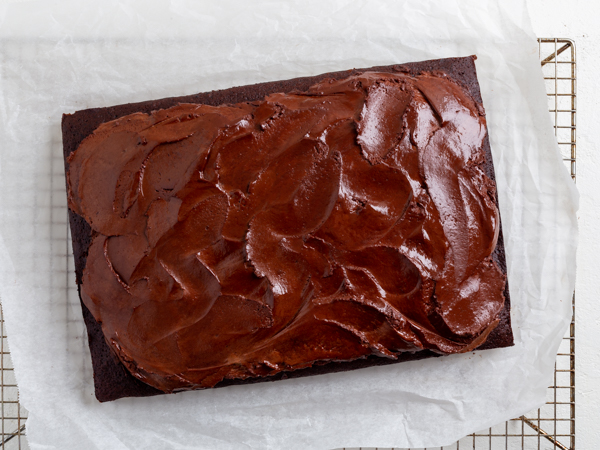 Gâteau au chocolat végétalien glacé sur du papier parchemin, sur une grille de refroidissement