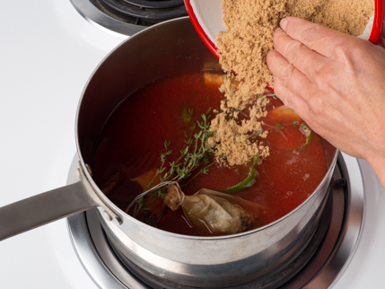 La cassonade se faisant ajouter à une casserole remplie de jus et d’herbes