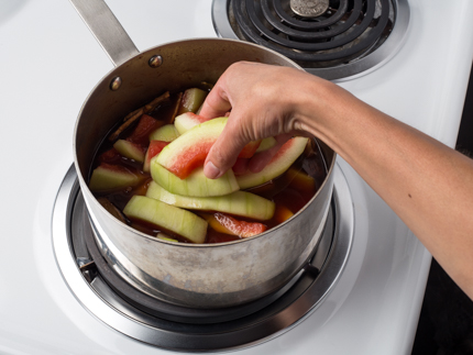 Des morceaux de blanc de melon d’eau se faisant ajouter à une casserole remplie de jus de fruit assaisonné