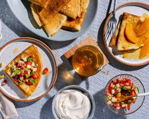 Assiettes de crêpes avec garnitures aux fruits et crème sûre fouettée au sucre brun