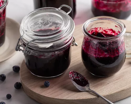 Confiture aux bleuets dans un pot et petit vase avec une cuillère de service