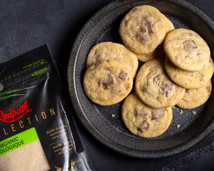 Biscuits au sucre avec morceaux de chocolat au lait présentés sur une assiette noire avec une serviette noire, sur comptoir en a