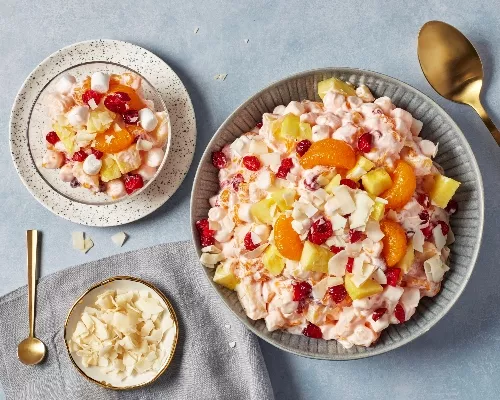 Un grand bol de salade d’ambroisie présenté à côté d’une portion individuelle servie dans un petit bol en verre