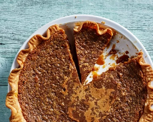 Une tarte au sucre avec deux pointes coupées, dont une manquante, dans un moule à tarte blanc